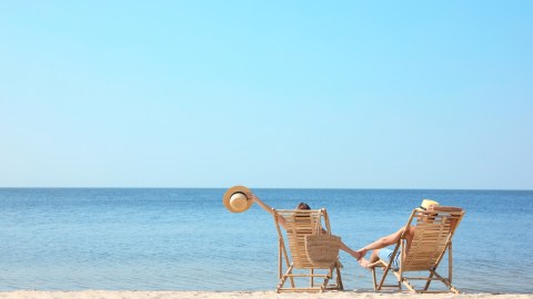 Young couple relaxing in deck chairs on beach