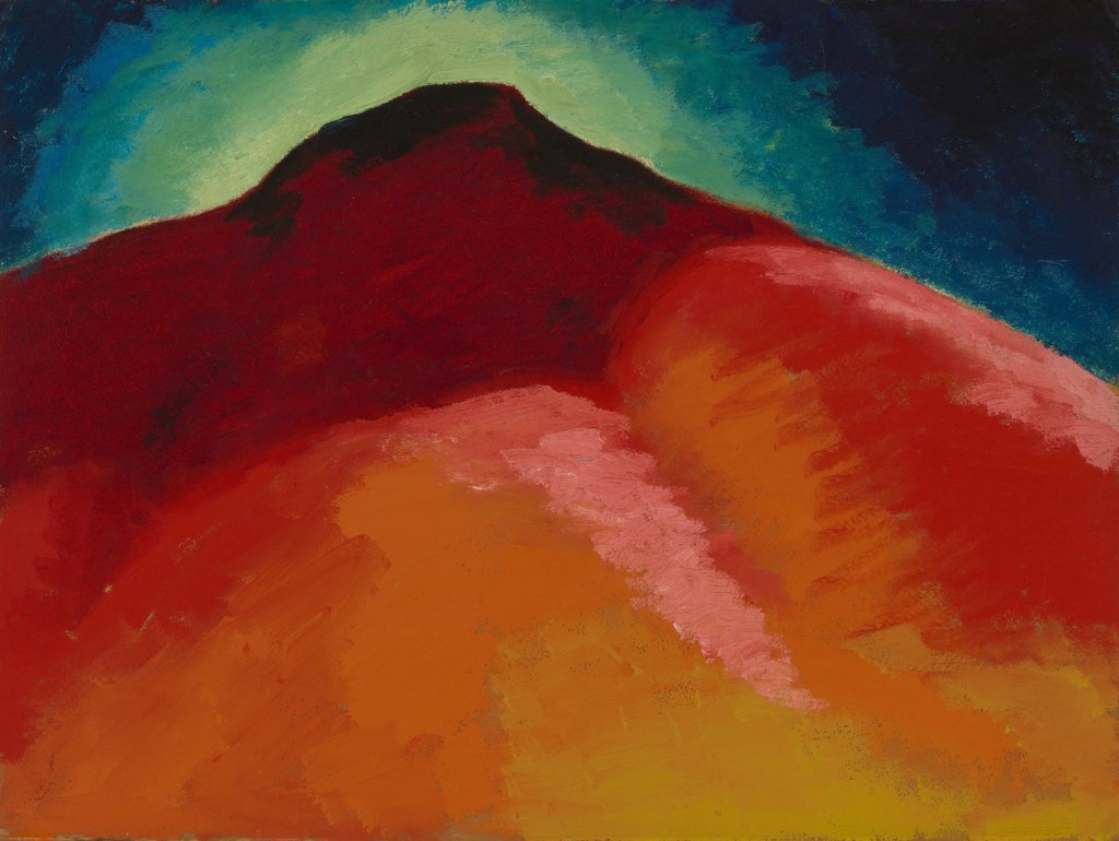 A dark green and blue sky gives way to a dark red to lighter orange mountain range in the foreground.