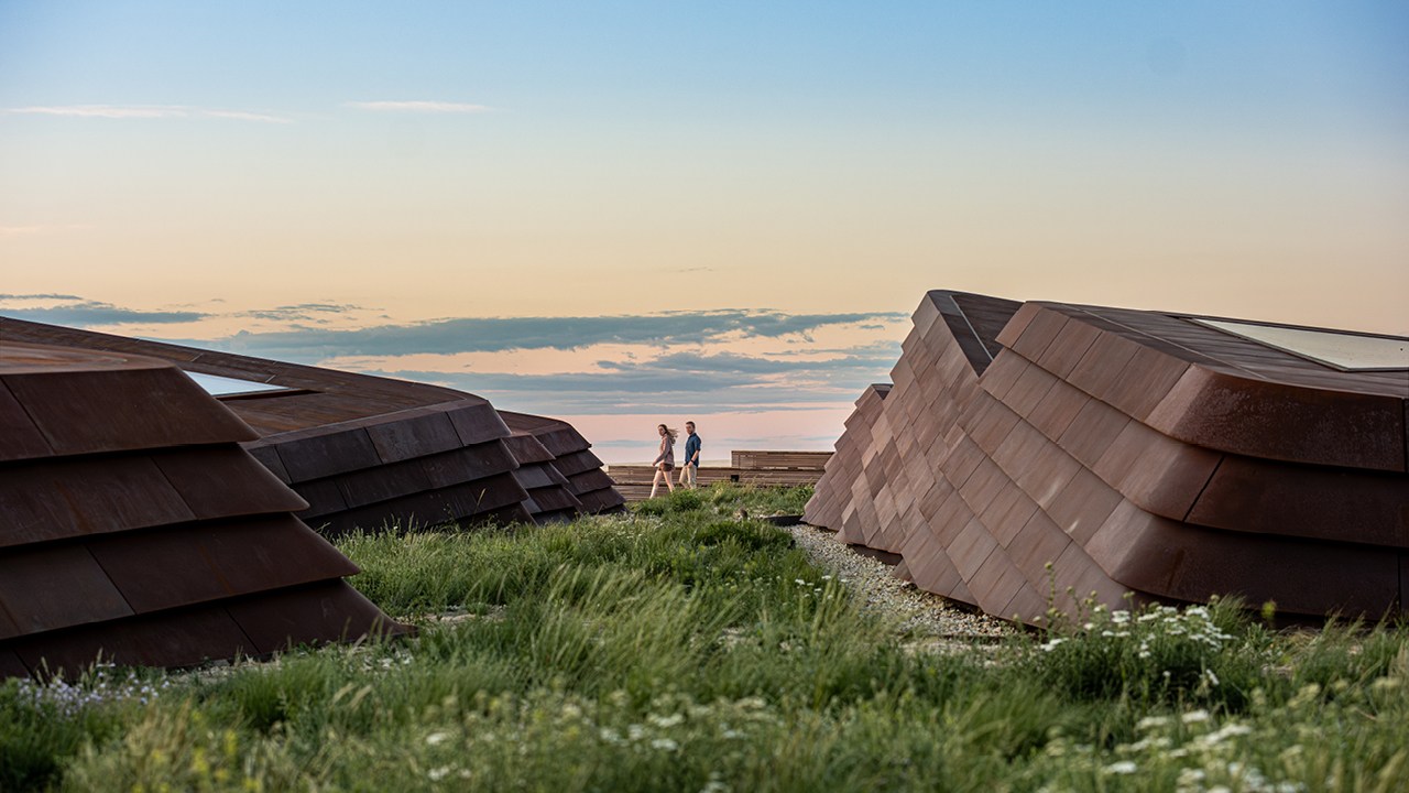 People walking on a green roof of the Theodore Roosevelt Presidential library, with a blue sky in the background