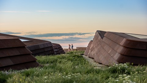 People walking on a green roof of the Theodore Roosevelt Presidential library, with a blue sky in the background