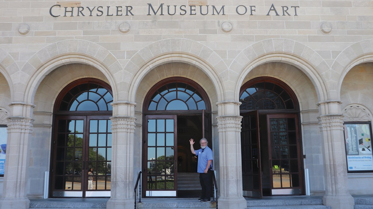 Man waving in front of the entrance of the Chrysler Museum of Art