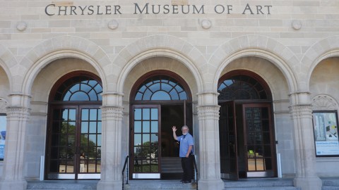 Man waving in front of the entrance of the Chrysler Museum of Art