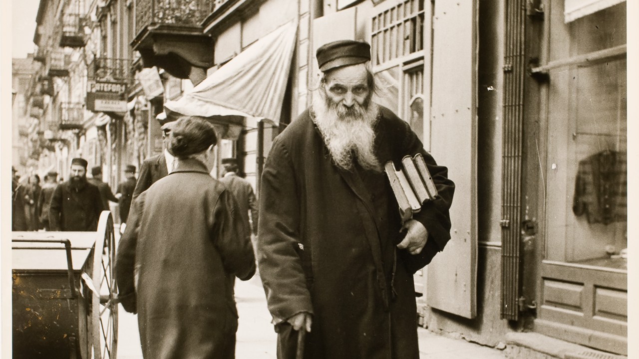 Jewish man walks on a street in an old black and white photograph.