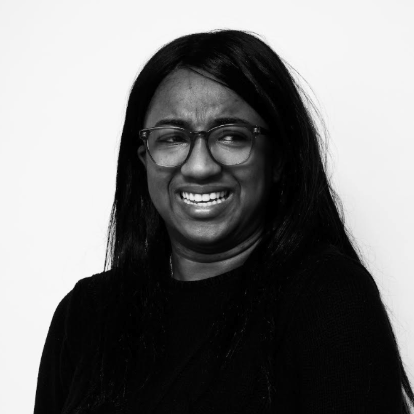 A black and white photo of Sierra Van Ryck deGroot, a black woman with long dark hair and glasses, looking off to the side.