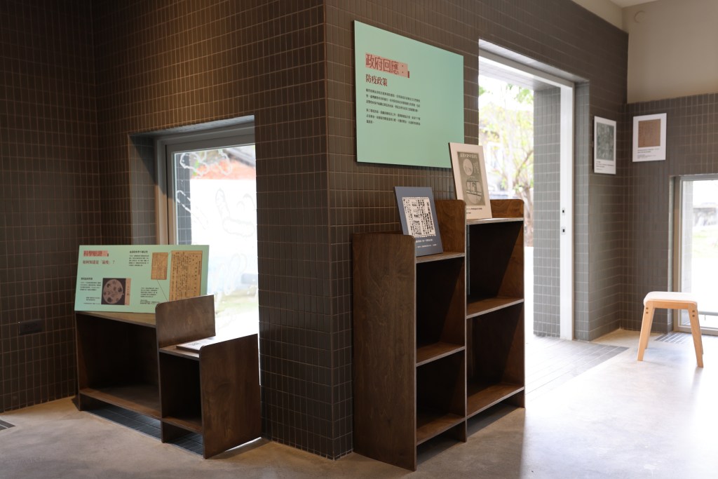 Display wall and case combining historical records and interpretive materials about plague governance and local responses.