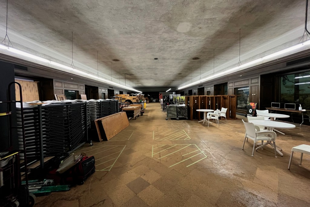 A large, rectangular room full of stored tables and chairs. 
